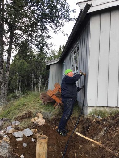 Arbeider jobber med vannuttak på husvegg