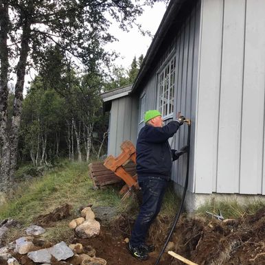 Arbeider jobber med vannuttak på husvegg