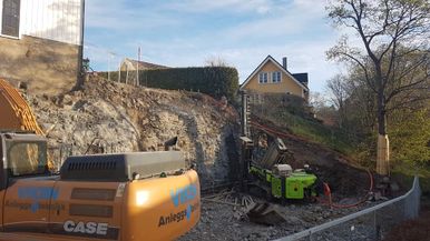 Gravemaskin og brønnboring på byggeplass