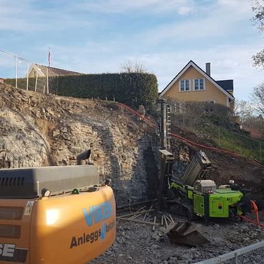 Gravemaskin og brønnboring på byggeplass
