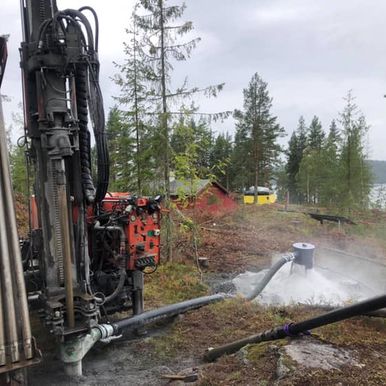 Brønnboring ved innsjø i skog